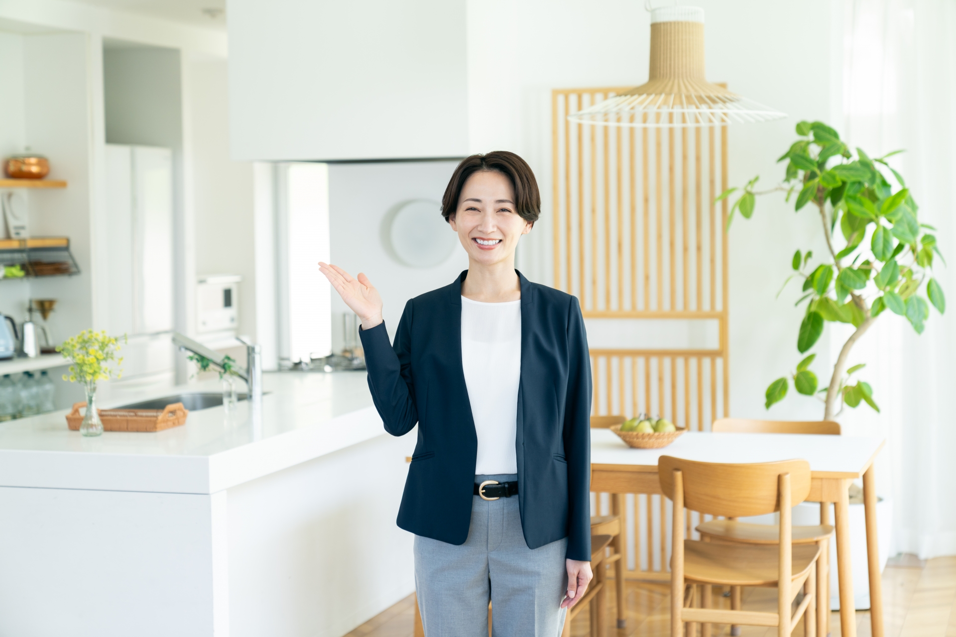 不動産売却の相談に対応する、明るいキッチンで笑顔の女性専門家