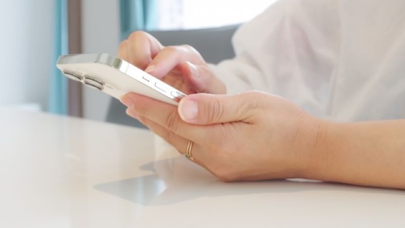 スマートフォンでSNS運用を行うユーザーの手元。オウンドメディア集客のポイントとなる日々の投稿や、フォロワーとのコミュニケーションをスマホ操作で表現。