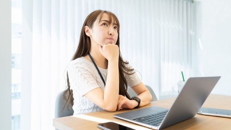 オウンドメディアの戦略立案が難しいと感じ、パソコンの前で悩み考え込むマーケティング担当者の様子。