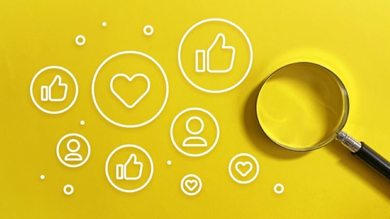 オウンドメディア集客に欠かせないSNS運用の分析イメージ。黄色い背景に「いいね」や人物アイコンが散りばめられ、フォロワーを増やすための調査を虫眼鏡で表現。